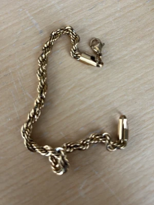 Guld armband - Snyggt armband i guldfärgad metall med tvinnad kedja och karbinlås. Armbandet har en klassisk och stilren design som passar till många olika looks. Perfekt accessoar för dig som gillar en enkel men ändå iögonfallande stil.