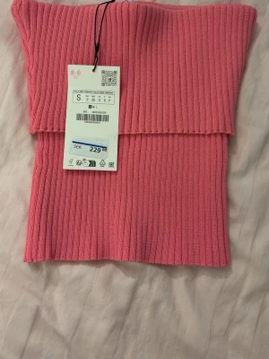 Rosa topp - Trendig rosa bandeau topp från Zara i ribbad stickad kvalitet. Toppen är axelbandslös och har en croppad passform som passar perfekt till sommaren. Enkel men snygg. Aldrig använd, lappen finns kvar på