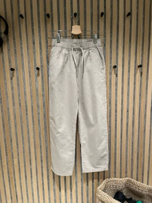 Beiga linnebyxor med dragsko  - Snygga linnebyxor i beige med avslappnad passform och elastisk midja med dragsko. Byxorna har två fickor och i nyskick.