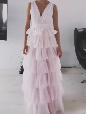 Bubbleroom klänning - Helt ny (enbart provad) Bubbleroom långklänning i ljusrosa med flera lager volanger och djup v-ringning både fram och bak. Klänningen är ärmlös och har en romantisk look som verkligen sticker ut. Perfekt för dig som vill ha något extra till speciella tillfällen.
