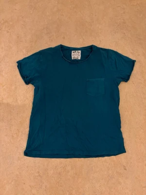 Blå kortärmad t-shirt med ficka - En enkel blå t-shirt från Monki med rund halsringning och en liten bröstficka. T-shirten har korta ärmar och är gjord i mjuk bomull, perfekt för en avslappnad stil. Vid mer info kontakta gärn! ABS! Pris går att diskutera! 