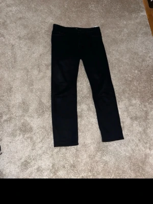 Svarta jeans från BOSS - Snygga svarta jeans från BOSS med klassisk femficksdesign och raka ben. Jeansen har diskret logga på myntfickan och är tillverkade i ett mjukt denimtyg som sitter skönt. Perfekta för dig som gillar stilrena och tidlösa plagg.