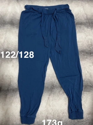 Mörkblå byxor med knytband - Säljer ett par mörkblå byxor med avslappnad passform och elastiska muddar vid bensluten. Byxorna har ett matchande knytband i midjan för extra stil och komfort. Perfekta för en chill och bekväm look.🌸 Fint använt skick. Storlek 122/128