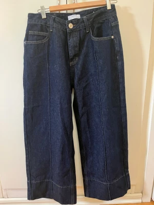 Mörkblå vida jeans från Lafemmmewandere - Snygga mörkblå jeans från Lafemmewandere med raka, vida ben och markerade sömmar framtill. Klassisk femficksmodell med hög midja och breda benslut. Tillverkade i kraftig denim med tydliga kontrastsömmar. Perfekta för en trendig och avslappnad look.  Storlek 27 (38/40)