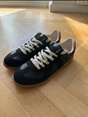 Svarta MM Skor  med kvitto Maison Margiela Sneakers  - Säljer dessa helt nya Maison Margeila sneakers köpt för 7000kr, kvitto medföljer. Passar med mycket outfits och är skjukt sköna. Box och tillbehör är med såklart. Gör gärna av er vid frågor.