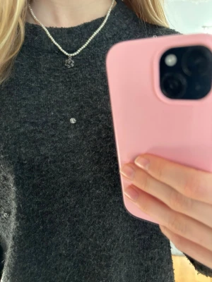 Pärlhalsband med svart blomberlock - Säljer ett stilrent halsband med vita pärlor och en svart blomformad berlock. Perfekt accessoar för dig som vill ha något unikt och trendigt.💓💓🩷🌸🌺💞🥰