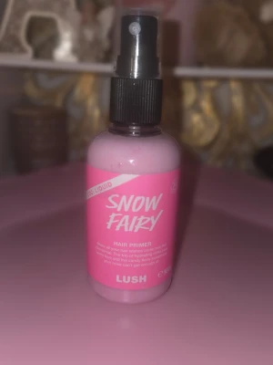 LUSH Snow Fairy Hair Primer - LUSH Snow Fairy Hair Primer är en rosa hårprimer i sprayflaska. Produkten är flytande och kommer i en smidig plastflaska med svart spraymunstycke. Perfekt för att ge håret extra fukt och skydd innan styling.