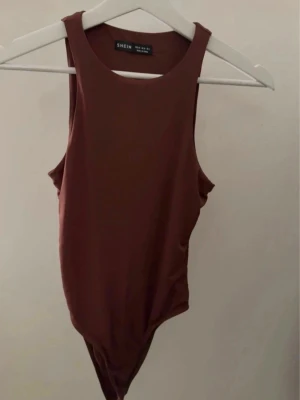 Brun body från SHEIN - Brun body från SHEIN med rund halsringning. Tillverkad i mjukt och stretchigt material som sitter skönt mot kroppen. Ny utan prislapp. 