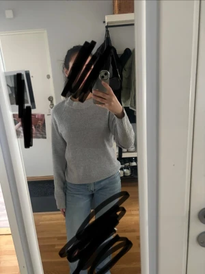 Ljusgrå basic stickad tröja - Enkel och stilren ljusgrå stickad tröja med rund halsringning och långa ärmar. Tröjan har en rak passform och är perfekt att matcha med jeans för en avslappnad look. Materialet ser mjukt och bekvämt ut.