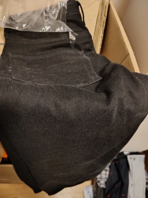 Svarta raka jeans - Säljer ett par svarta jeans med klassisk femficksdesign och raka ben. Jeansen har en enkel bakficka och är tillverkade i ett slitstarkt denimtyg. Perfekta för dig som gillar en stilren och tidlös look. Demin by H&M 