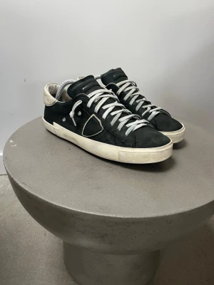 Philippe Model svarta sneakers - Mörk gröna  sneakers från Philippe Model med vita detaljer och vit sula. Skorna har en låg silhuett, vita skosnören och en kontrasterande beige hälkappa. Tillverkade i läder med klassisk design och diskret logotyp på sidan.