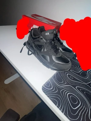 Nike Air Max svart sneaker - Snygga helsvarta Nike Air Max sneakers med klassisk design och synlig Air-dämpning i sulan. Skorna har en låg silhuett, svarta skosnören och ovandel i en mix av läder och syntetmaterial. Perfekta för dig som gillar stilrena och sportiga sneakers.