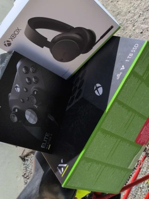 Xbox Series X 1TB med Elite-kontroll - Xbox Series X spelkonsol med 1TB SSD, svart design och tillhörande Xbox Elite Series 2 trådlös handkontroll samt Xbox trådlöst headset. Allt i stilren svart färg och robust material, perfekt för gaming på hög nivå.
