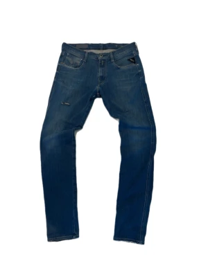 Blå slim fit jeans från replay - Snygga blå slim fit jeans från replay med klassisk femficksdesign och diskreta slitningar framtill. Jeansen har en liten logotypdetalj vid fickan och är tillverkade i stretchig denim för en bekväm passform.  