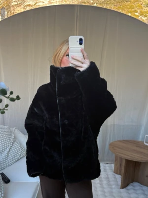 Svart fuskpälsjacka - Mysig svart  fuskpälsjacka med hög krage och knäppning framtill. Från Gina tricot, ny utan prislapp