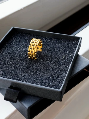 Guldfärgad bred ring i länkdesign - Snygg guldfärgad ring med bred länkdesign som ger en modern och trendig känsla. Ringen har en öppen baksida vilket gör den justerbar i storlek. Perfekt accessoar för dig som gillar statement-smycken och vill sticka ut lite extra.