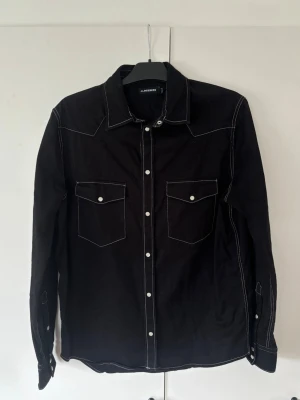 Svart J.lindeberg Jeanskjorta herr M - Helt ny populär unik J.lindeberg Jeanskjorta i storlek M. Utmärkt nyskick inga som helst defekter! Grym passform och ett helt otroligt plagg perfekt för alla tillfällen!