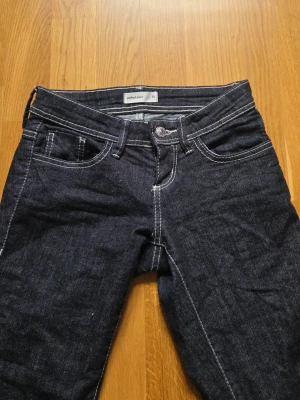 Mörkblå jeans från gina tricot - Snygga mörkblå jeans från gina tricot med klassisk femficksdesign och kontrasterande vita sömmar. Jeansen har utsvängda ben och är tillverkade i slitstarkt denim-material. Perfekt för dig som vill ha en tidlös och stilren look.