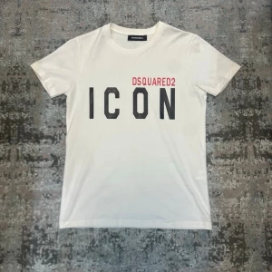 Vit ICON t-shirt - Vit t-shirt med trycket 'ICON' i svart på bröstet. Klassisk passform med rund hals och korta ärmar. Perfekt för en trendig och avslappnad stil.