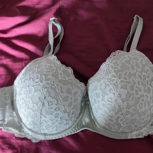 Grön nyans spets-bh med bygel 85C hunkemöller  - Säljer en ljusgrå bh med vacker spets och bygel. Bh:n har vadderade kupor, justerbara axelband och hakknäppning bak. Spetsdetaljerna ger en romantisk känsla och materialet är mjukt mot huden. Använd 2 ggr nypris 429 kr