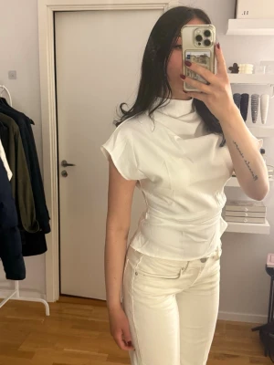 Vit kortärmad blus med hög krage - Snygg vit blus med hög krage och korta ärmar. Figursydd modell med markerad midja och stilren design. Perfekt att styla med jeans eller kjol för en trendig look. Den är aldrig använd utan endast testad. Storlek S. Från Shein 
