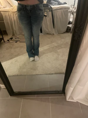 Blå bootcut jeans - Snygga blå bootcut jeans med lätt slitna detaljer och klassisk femficksdesign. Jeansen har låg midja och är tillverkade i denim med lite stretch för skön passform. 