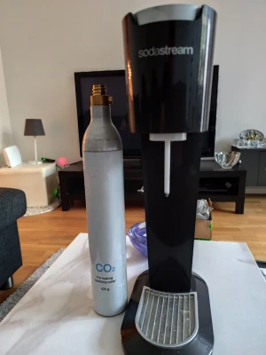 Sodastream maskin med tom gaspatron - Säljer en svart Sodastream maskin tillsammans med en silverfärgad CO2-gaspatron på 425g. Perfekt för att göra eget bubbelvatten hemma. Maskinen har en stilren design i plast och metall.