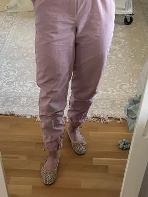 Ljuslila leggings med resår - Säljer ett par ljuslila leggings med resår i midjan och vid bensluten. De har en avslappnad passform och är tillverkade i ett tunt, mjukt tyg som känns skönt mot huden. Perfekta för en chill och trendig look.