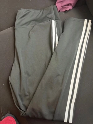 Svarta leggings med vita ränder - Snygga svarta leggings med två vita ränder längs benen. Perfekta för en sportig look och tillverkade i stretchigt material som sitter skönt. Hög midja för extra komfort och stilren design som passar till många outfits.