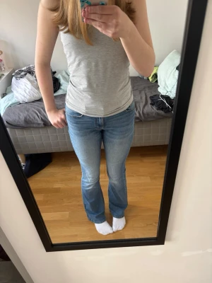 Ljusblå bootcut jeans - Säljer ett par ljusblå bootcut jeans med klassisk femficksdesign och normal midja. Jeansen har en snygg tvätt och är tillverkade i ett mjukt denimtyg som sitter bekvämt. Perfekta för dig som gillar en avslappnad men trendig stil. Super sköna byxor men fortfarande fina och stiliga jeans. 