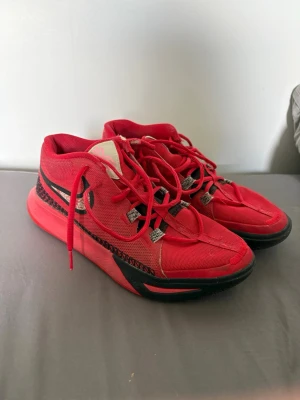 Kyrie basketskor - Snygga röda Nike basketskor med svart swoosh och detaljer. Skorna har mesh-överdel för bra ventilation, röda skosnören och svart mönster längs sulan. Perfekta för basket eller streetwear och har en modern, sportig look. Skick 8/10. Kom privat för mer info!