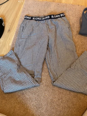 Rutiga pyjamasbyxor från Björn Borg - Snygga och bekväma pyjamasbyxor från Björn Borg med svartvitt rutmönster och bred resår i midjan med logga. Perfekta för chillkvällar hemma. Tillverkade i mjukt tyg som känns skönt mot huden.