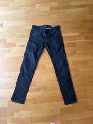 Mörkblå slim fit jeans från Replay - Snygga mörkblå slim fit jeans från Replay med klassisk femficksdesign och diskreta sömmar på bakfickorna. Jeansen har en smal passform och är tillverkade i ett stretchigt denimtyg som ger en bekväm känsla hela dagen.