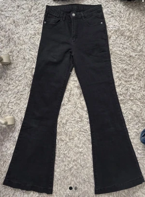 Svarta bootcut jeans med hög midja - Snygga svarta bootcut jeans med hög midja .Jeansen har utsvängda ben och stängs med knapp och dragkedja. Används inte för har för många jeans men väldigt snygga på! Inte alls använda