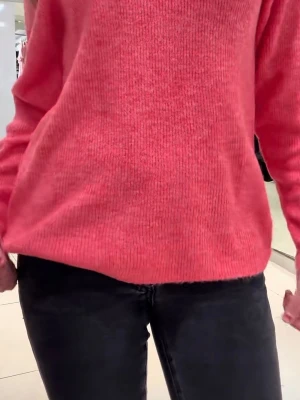 Korallrosa stickad tröja - Mysig stickad tröja i en snygg korallrosa färg. Tröjan har en klassisk rak passform med långa ärmar och rund halsringning. Perfekt att matcha med jeans för en avslappnad look.