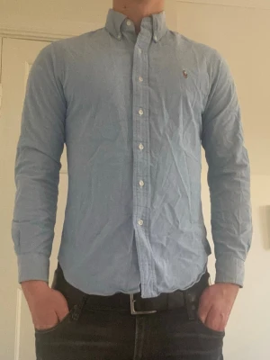 Ljusblå Polo Ralph Lauren skjorta  - Klassisk ljusblå skjorta från Ralph Lauren med button-down krage och broderad logga på bröstet. Står storlek M men passar som S. Modellen är 189
