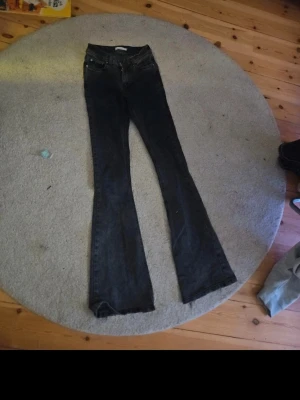 Svarta bootcut jeans - Säljer ett par svarta bootcut jeans med klassisk femficksdesign och normal midja. Jeansen har utsvängda ben och är tillverkade i denim. Perfekta för dig som gillar en retroinspirerad look.