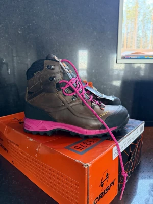 Crispi Valdres GTX kängor brun/magenta - Snygga och robusta kängor från Crispi i modellen Valdres GTX. Färgen är brun med magentafärgade detaljer och snören. Kängorna har högt skaft, grov sula och är tillverkade i slitstarkt material med Gore-Tex för vattentäthet. Perfekta för äventyr och uteliv.