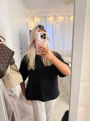 Svart oversized stickad tröja mohair Gina Tricot  - Säljer en svart oversized stickad tröja med kortare ärmar och rund hals. Tröjan har en enkel och avslappnad passform, perfekt för en chill och stilren look. Passar till både jeans och mjukisbyxor.