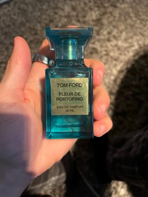 Tom Ford Fleur de Portofino 50 ml - Tom Ford Fleur de Portofino Eau de Parfum i en elegant, turkosblå glasflaska med guldlabel. Flaskan rymmer 50 ml och har en lyxig, fyrkantig design med tydliga linjer och exklusiv känsla. Perfekt för dig som gillar exklusiva dofter och snygg design. Är knappt använd kanske max 2 ml