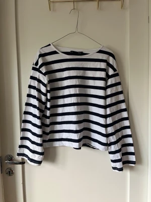 Randig långärmad  - Snygg långärmad topp med marinblå och vita ränder. Klassisk rak passform och rund halsringning. Tillverkad i mjuk bomull, perfekt för en avslappnad stil.