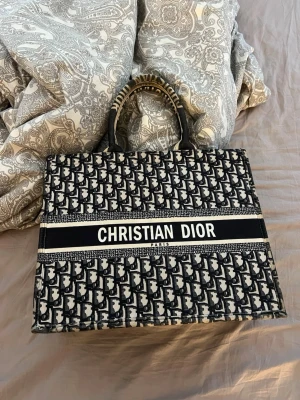 Stor Tote shoppingväska - Säljer en strand och shoppingväska i svart och beige canvas med det klassiska D mönstret. Väskan har två handtag och stor logga framtill. Perfekt för dig som vill ha en lyxig och rymlig väska med statement-känsla