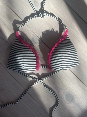 SKRIV INNAN KÖP! - Snygg bikiniöverdel med svartvita ränder och färgglad rosa volangkant från calzedonia i modellen cobey. kommer inte ihåg om  den var i s eller xs men skulle gissa S fast den passar som en xs❣️ SKRIV INNAN TRYCK PÅ KÖP