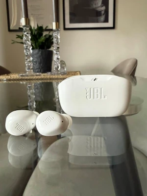 Vita trådlösa in-ear hörlurar JBL - Trådlösa JBL hörlurar. Det finns några små fläckar på fodralet som jag ej fått bort men annars är dom felfria och batteriet är bra. Ca 1 år gamla, laddas med USB c - kabel.