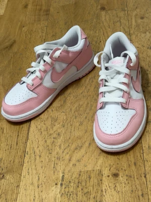 Nike Dunk Low rosa och vita sneakers - Jag säljer ett par rosa/vita Nike-skor i mycket fint skick.  Använda få gånger och fortfarande väldigt fina. Skriv gärna om du är intresserad eller vill ha fler bilder 