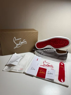 Gråa Christian Louboutin sneakers - Säljer ett par as feta Christian Louboutin sneakers i grå mocka med den sjuka röda sulan 🔥 Riktigt clean modell som passar till typ allt och gör outfiten mycket fetare direkt.  Skorna är i väldigt fint skick och kommer med allt original:  * Kartong * Dustbag * Kvitto/papper * Tillbehör enligt bilderna  Perfekta om du vill ha något exklusivt men fortfarande stilrent 👌  Storlek: 42 Skick: HELT NY  Pris: 2499 (priset går att diskutera)