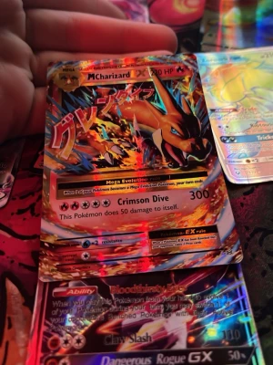 Pokémonkort Mega Charizard EX - Säljer ett glansigt Pokémonkort av Mega Charizard EX med japansk text och färgstark design. Kortet har holografisk yta och visar Charizard i eldig pose. Perfekt för samlare eller Pokémonfans som vill utöka sin samling.