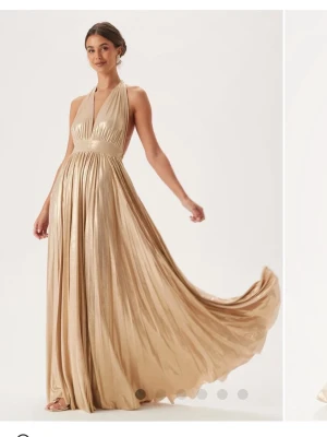 Champagnefärgad balklänning  - Säljer min underbara balklänning 🥹Jag är 160 cm för referens, är avklippt längst ner en bit men inget som syns eftersom det är så mycket tyg. Man knyter bak i nacken, går att justera hur högt/ lågt man vill ha midjan. Dragkedja i sidan, känns inte tung att ha på sig. Har massvis med bilder, skriv om du vill ha fler eller mer info 🩷