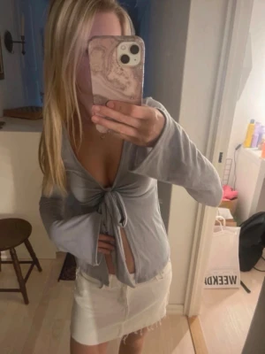 Ljusblå omlottopp med knyt - Trendig ljusblå omlottopp med långa ärmar och knyt framtill. Djup v-ringning och croppad passform ger en snygg och modern look. Perfekt att styla med kjol eller jeans.