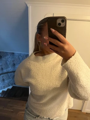 Krämvit Teddy tröja - Mysig krämvit teddy tröja med grov struktur och bred ribbad krage. Tröjan har en avslappnad passform och långa ärmar, perfekt för kyligare dagar.🧸💓